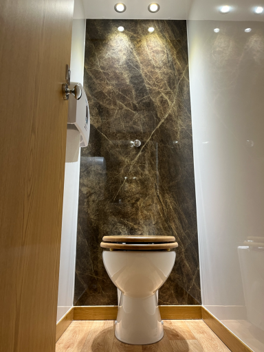 Modern bathroom with a wooden toilet seat and marble-effect wall.