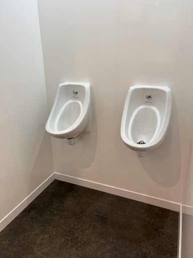 Two white urinals mounted on a clean, light-coloured wall.