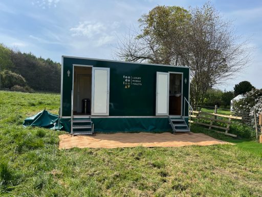 Green mobile structure on a grassy field with steps and doors on either side.