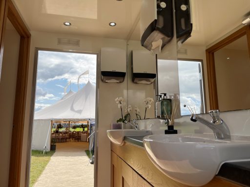 Interior of a modern bathroom with sinks, mirrors, and a view of an outdoor event.