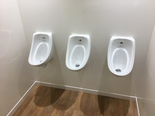 Three white urinals against a plain wall in a restroom.