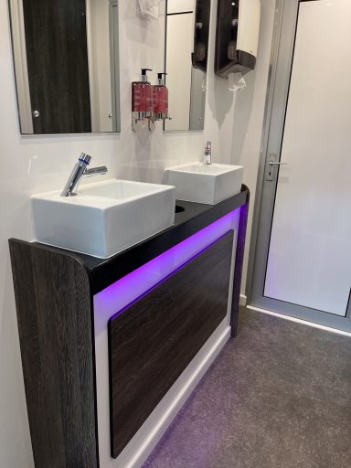 Modern bathroom vanity with two sinks, mirrors, and ambient purple lighting.